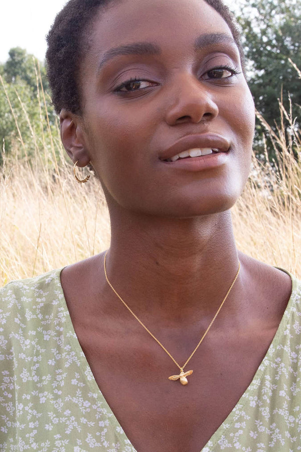 Model wearing the Baby Bee necklace in gold colour from the brand ALEX MONROE