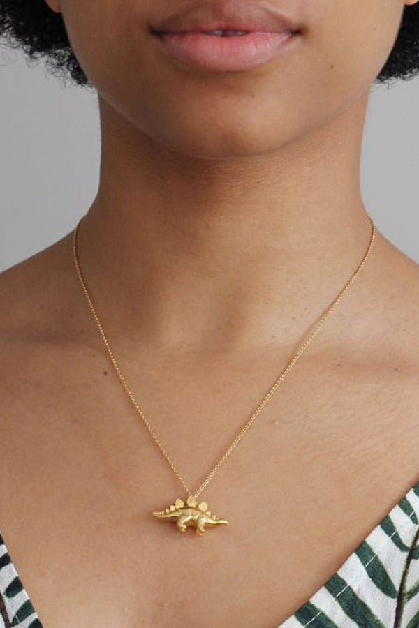 Model wearing the stegosaurus necklace in gold colour from the brand ALEX MONROE