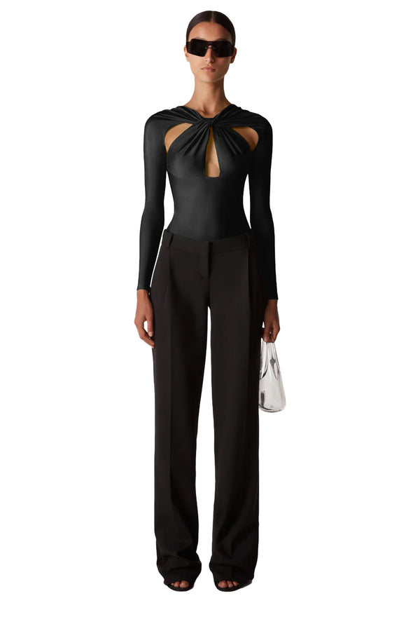 Model wearing the twisted cut-out bodysuit in black color from the brand COPERNI