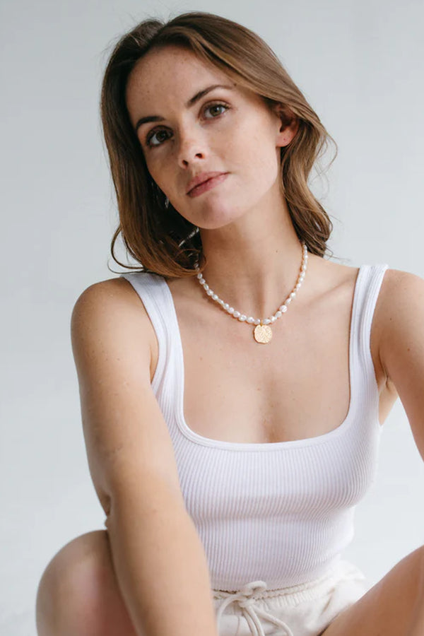 Model wearing the Rosa pendant-embellished pearl necklace in gold color from the brand GISEL B.