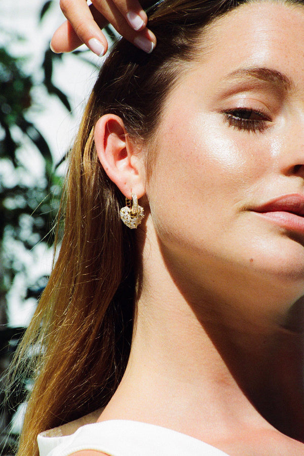 Model wearing the Puzzle Heart earrings in gold color from the brand CRYSTAL HAZE
