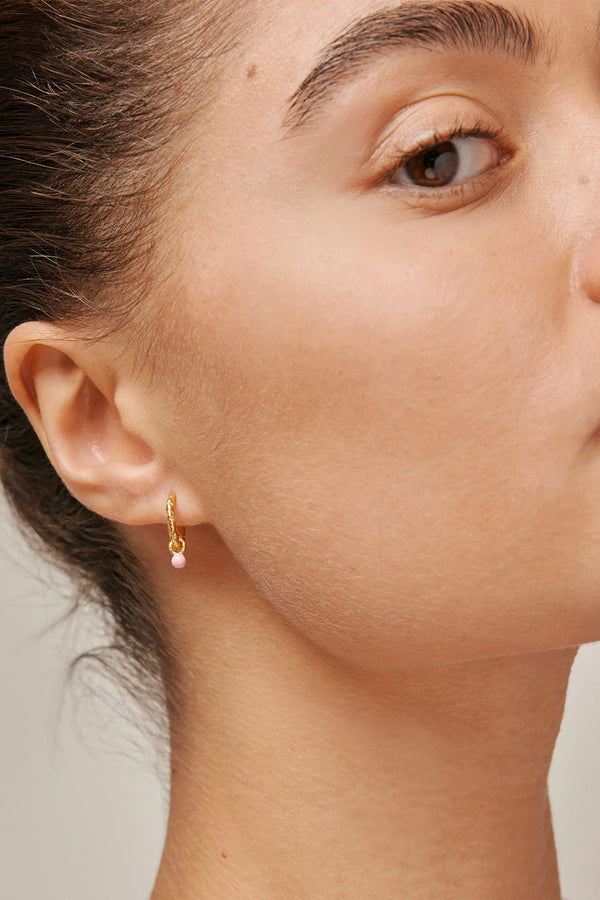 Model wearing the Belle hoop earrings in gold and light-pink colour from the brand ENAMEL COPENHAGEN