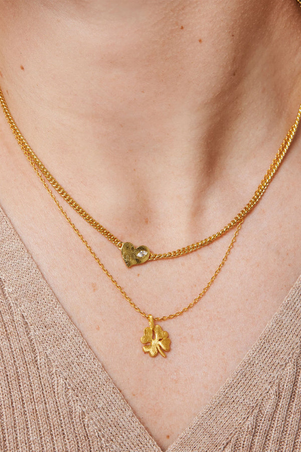 Model wearing the organic clover necklace in gold colour from the brand ENAMEL COPENHAGEN