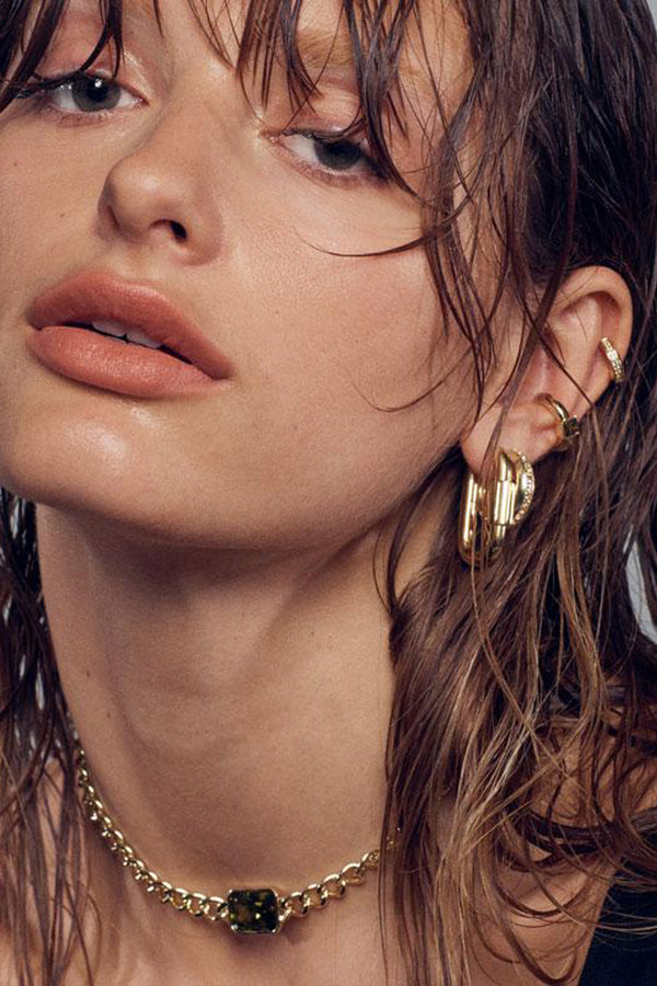 Model wearing the disengage XL hoop earrings in gold colour from the brand F+H JEWELLERY