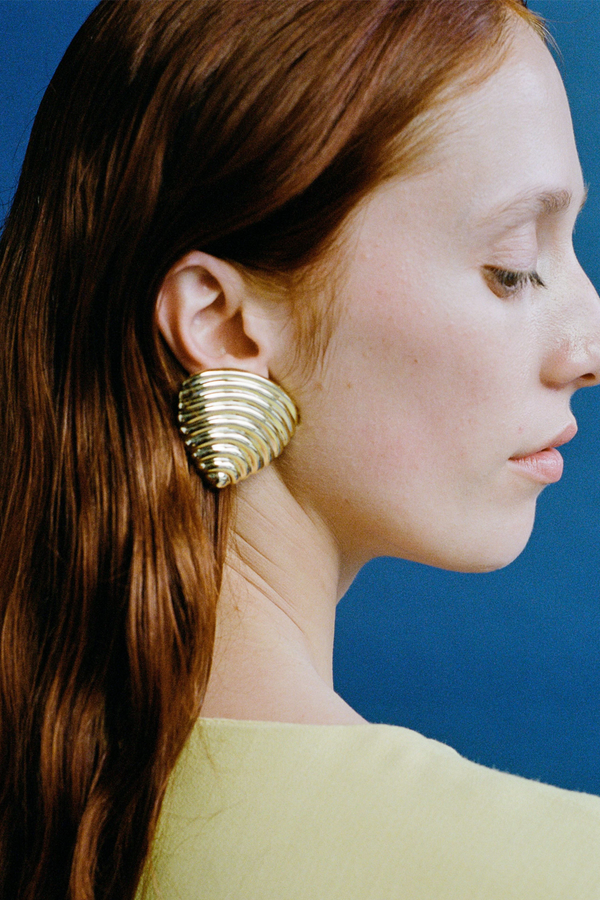 Model wearing the Celine stud earrings in gold colour from the brand JASMIN SPARROW