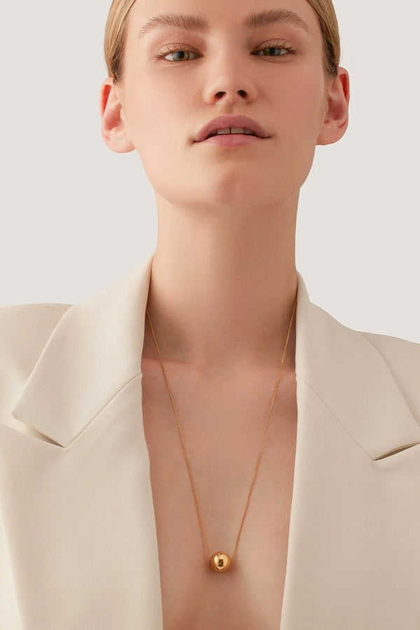 Model wearing the Aurora necklace in gold colour from the brand JENNY BIRD