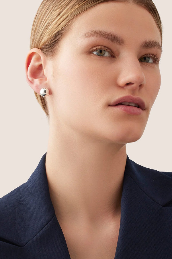 Model wearing the Aurora stud earrings in silver colour from the brand JENNY BIRD