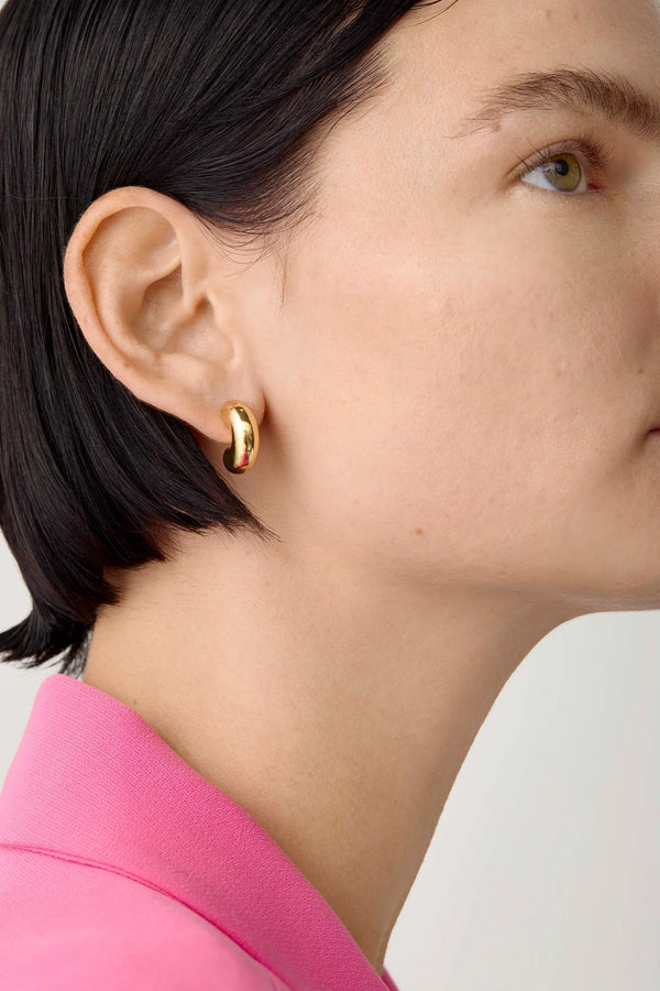 Model wearing the Tome small hoop earrings in gold colour from the brand JENNY BIRD