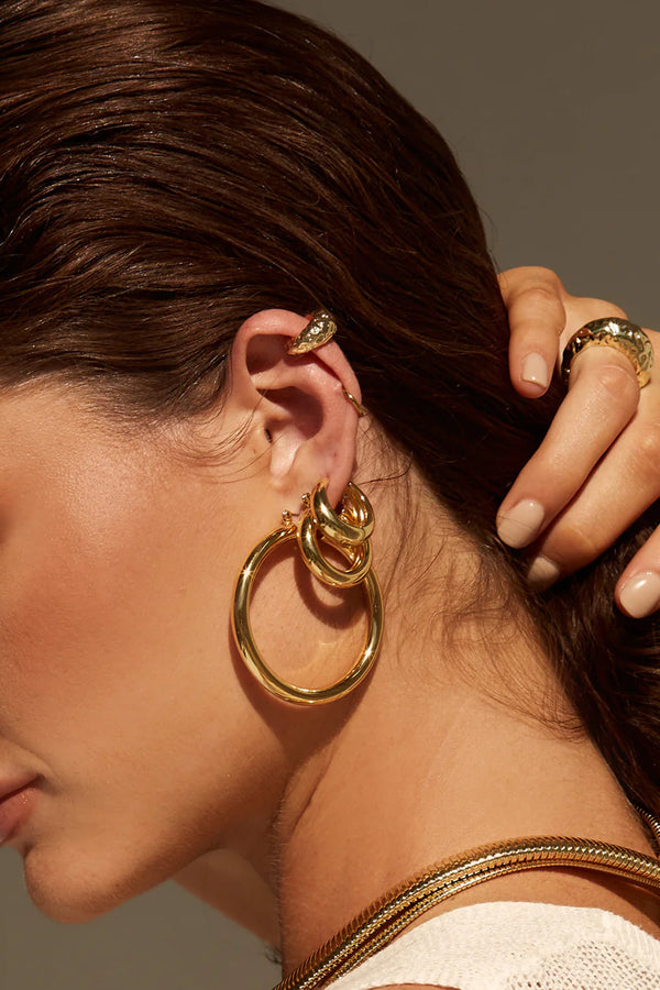 Model wearing the Amalfi tube hoop earrings in gold colour from the brand LUV AJ