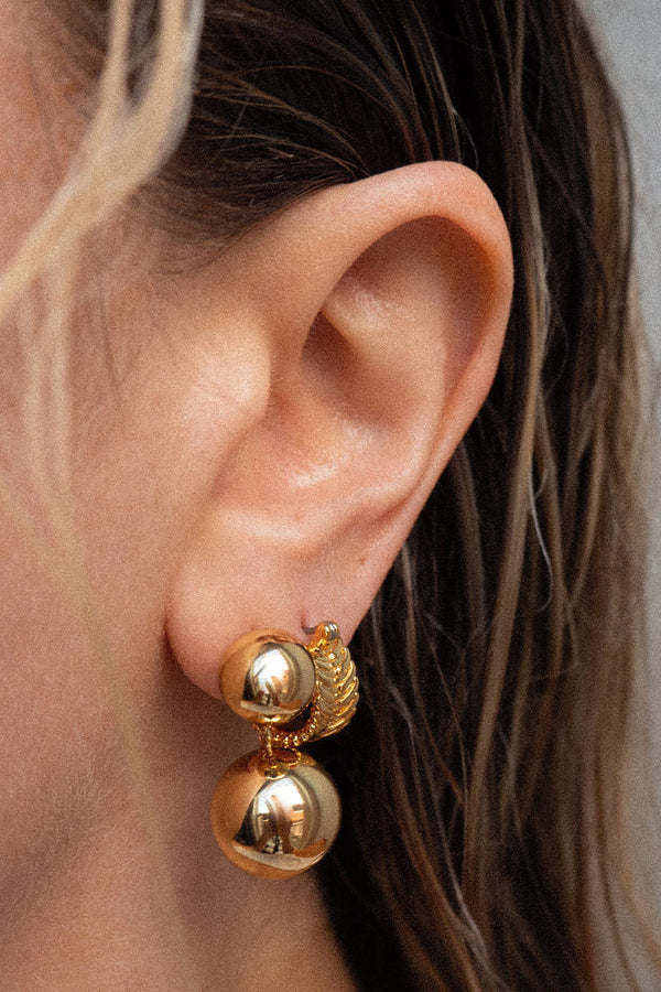 Model wearing the double ball stud earrings in gold colour from the brand LUV AJ