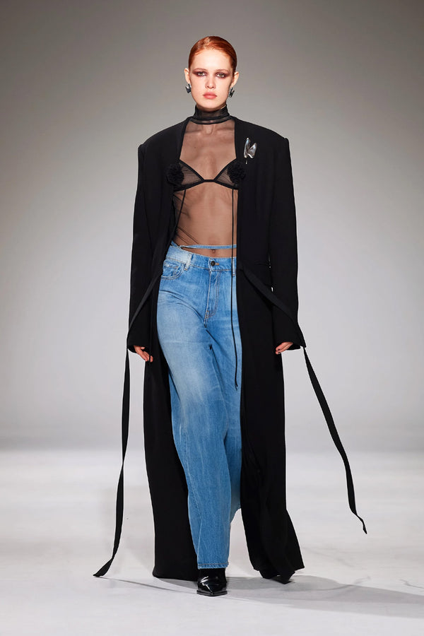 Model wearing the hip strap-detail boyfriend jeans in blue color from the brand NENSI DOJAKA