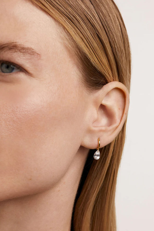 Model wearing the Aqua single hoop earring in gold and clear colours from the brand P D PAOLA