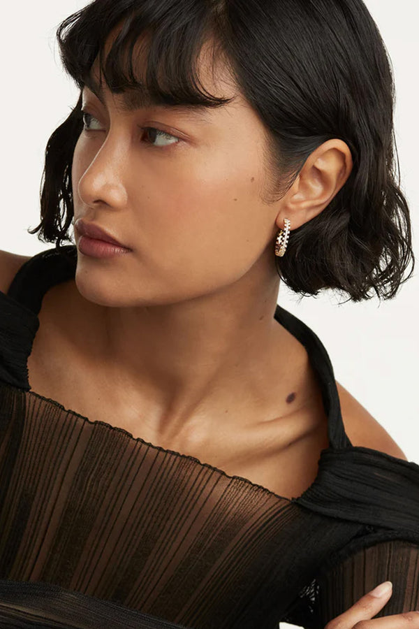 Model wearing the Crown earrings in gold and clear colours from the brand P D PAOLA