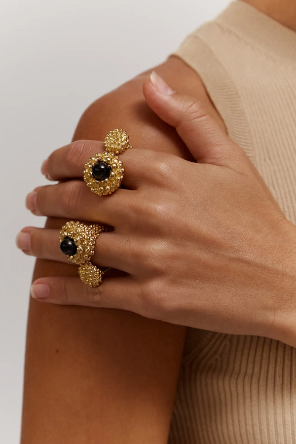 Model wearing the Karpos ring in gold and black colors from the brand PAOLA SIGHINOLFI