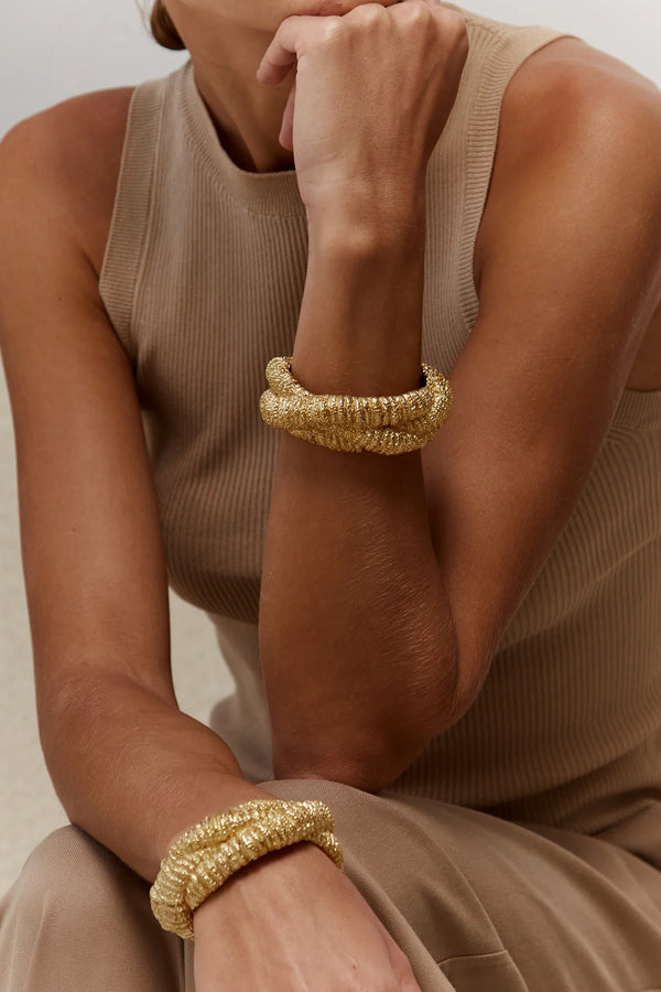 Model wearing the Nomad bracelet in gold colour from the brand PAOLA SIGHINOLFI