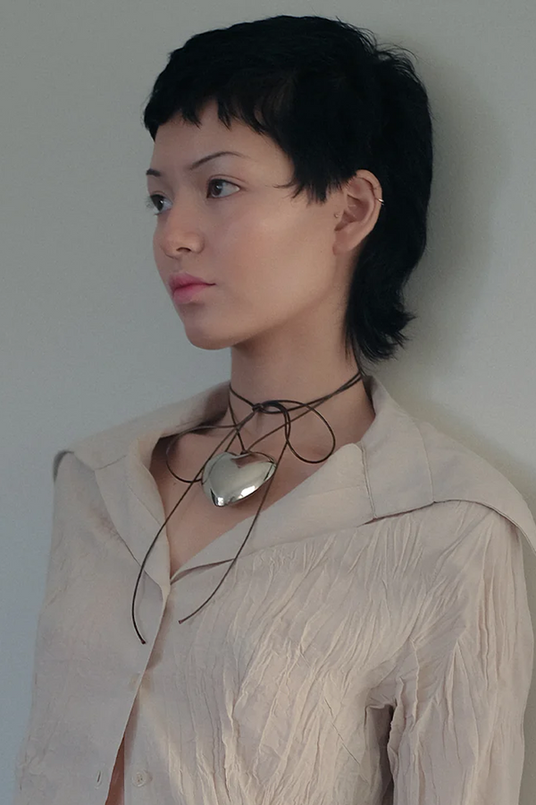 Model wearing the Spirit Big Heart necklace in silver and brown colours from the brand THE GOOD STATEMENT