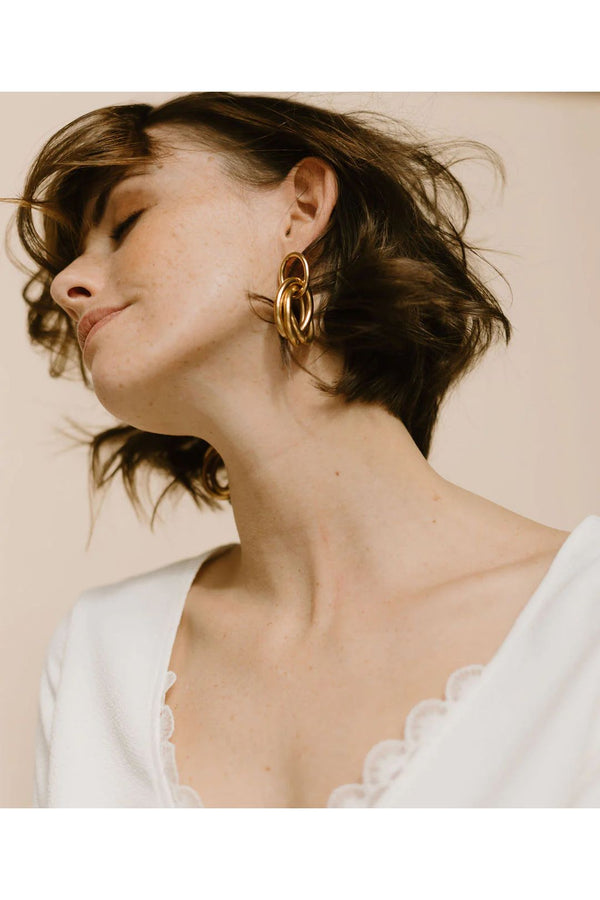 Model wearing the Elisabeth intertwined oval earrings in gold color from the brand GISEL B.